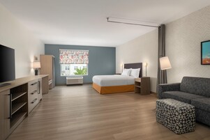 Una habitación de hotel moderna con cama, sofá, televisor y escritorio.