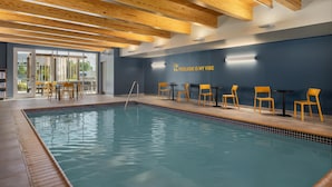 Un espace piscine avec un mur bleu, des poutres en bois au plafond et des chaises jaunes.