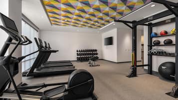 A gym with treadmills, weight machines, and a variety of dumbbells and exercise balls.