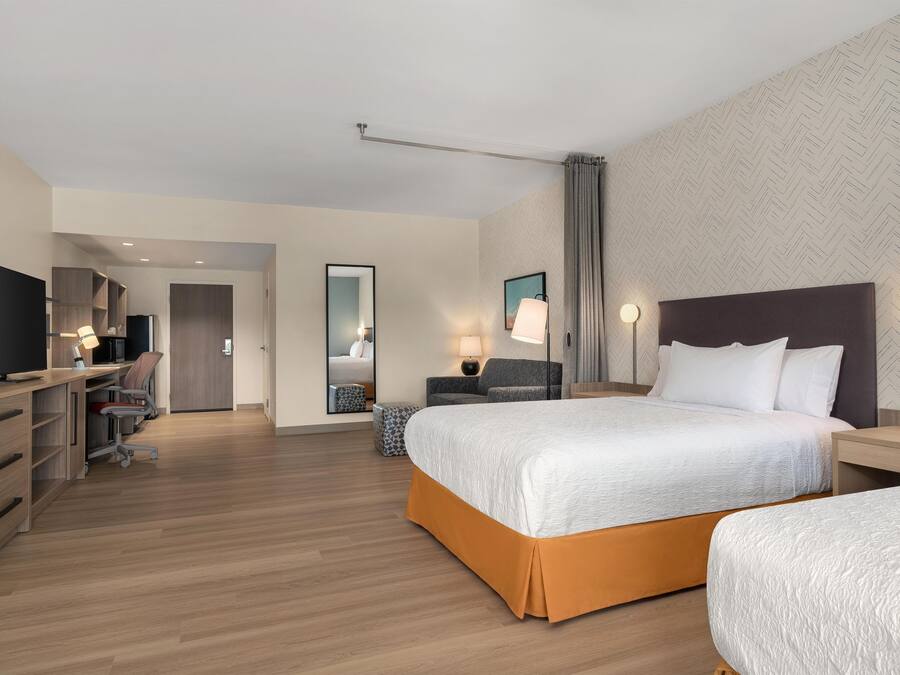 Habitación de hotel con cama, mesitas de noche, escritorio con silla, televisión y armario.