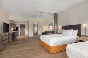Une chambre d’hôtel comprenant un lit, des tables de chevet, un bureau avec une chaise, une télévision et une armoire.