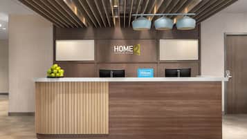 A hotel reception desk with a modern design, featuring a wooden panel and a glass display case with apples.