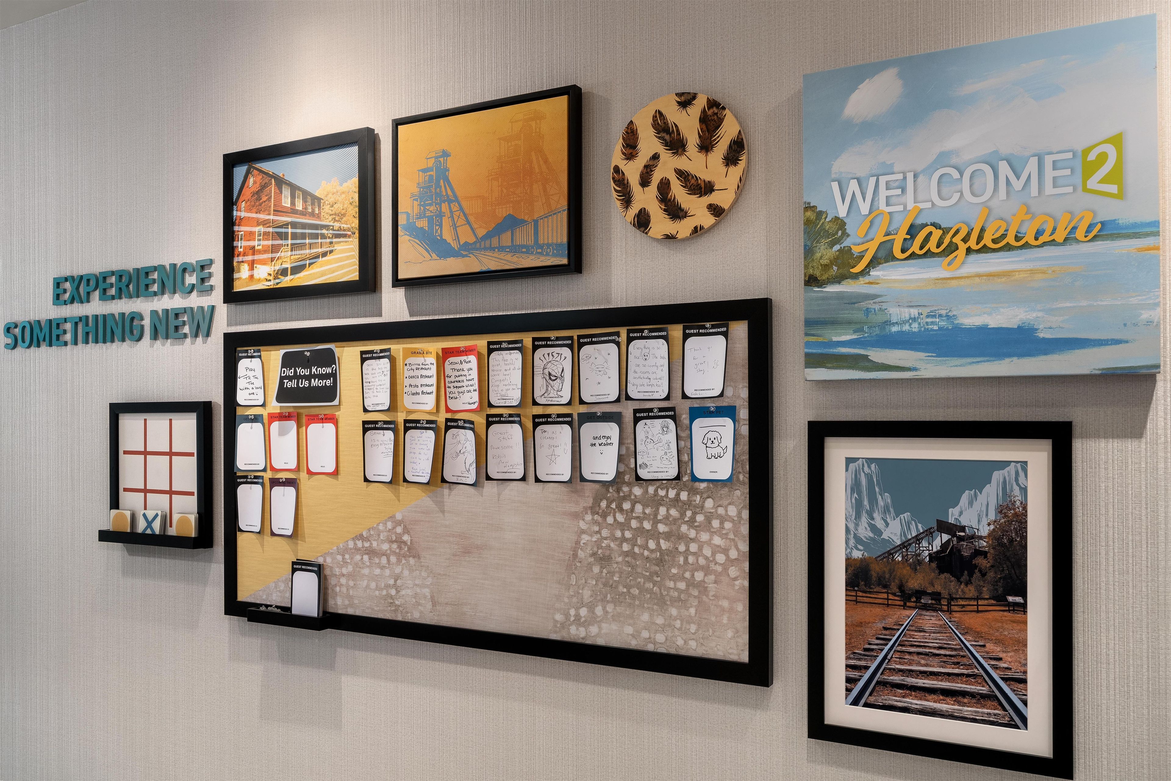 Een muur met diverse ingelijste kunstwerken, een bord met een welkomstboodschap en een selectie van aanbevelingen van gasten.
