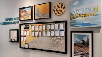 Een muur met diverse ingelijste kunstwerken, een bord met een welkomstboodschap en een selectie van aanbevelingen van gasten.