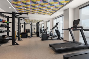 Une salle de sport équipée de matériel d’exercice, d’un tapis de course et dotée d’un plafond aux couleurs vives.