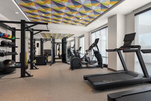 Un gimnasio con equipo de ejercicio, una cinta de correr y un techo colorido.