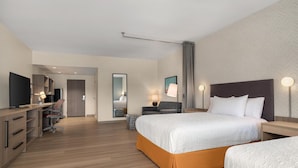 Une chambre d’hôtel comprenant un lit, des tables de chevet, un bureau avec une chaise, une télévision et une armoire.