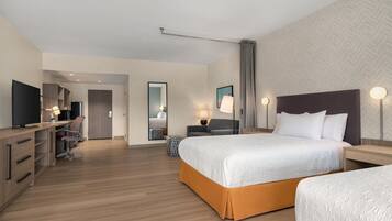 A hotel room with a bed, bedside tables, a desk with a chair, a television, and a wardrobe.