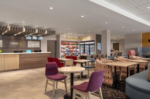 Un moderno vestíbulo de hotel con mostrador de recepción, zona de estar y bar de aperitivos.