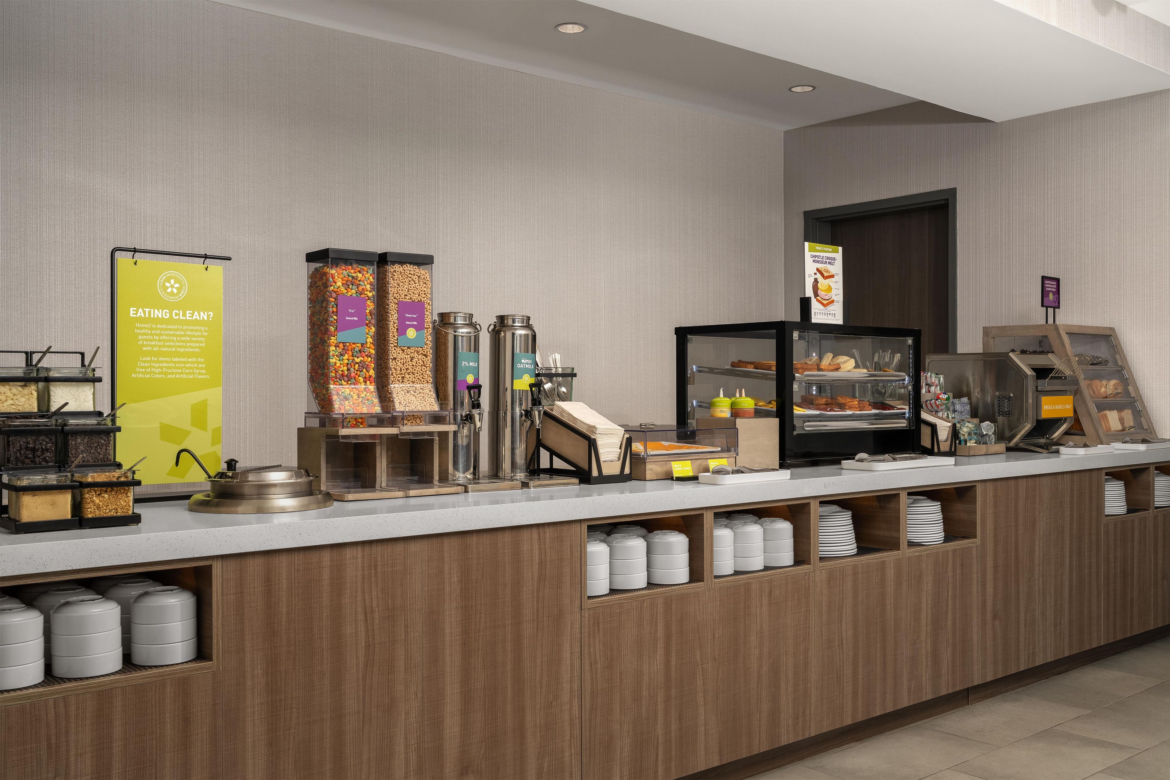 A self-service breakfast station with various food options and a sign promoting clean eating.
