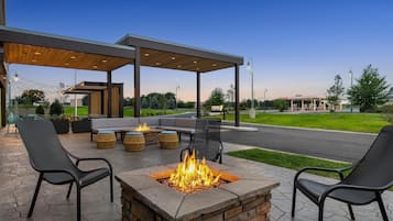 Un patio exterior con mobiliario, una chimenea y un área techada.