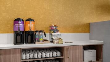 A coffee station with two coffee makers, a honey jar, and a coffee machine on a counter.