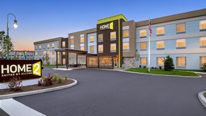 Un hôtel avec une enseigne « HOME 2 », plusieurs étages et une entrée bien éclairée.