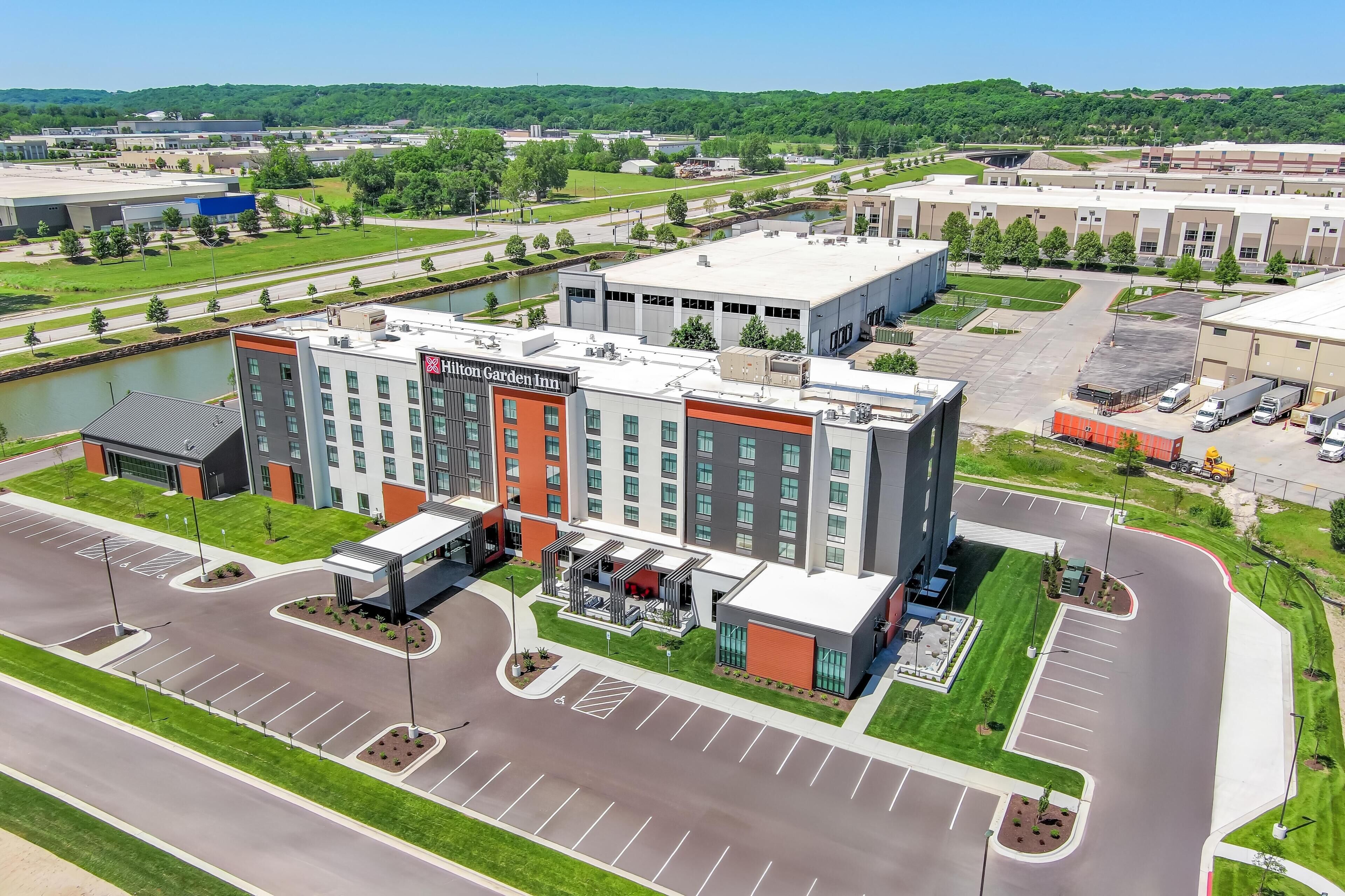 Een modern hotel met een goed zichtbaar Hilton Garden Inn bord, omringd door een parkeerplaats en een rivier.