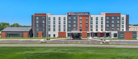 A modern Hilton Garden Inn with a central entrance, multiple floors, and a parking lot.