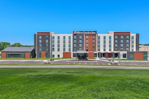 A modern Hilton Garden Inn with a central entrance, multiple floors, and a parking lot.