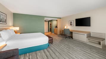 A hotel room with a bed, desk, chair, and a TV on the wall.