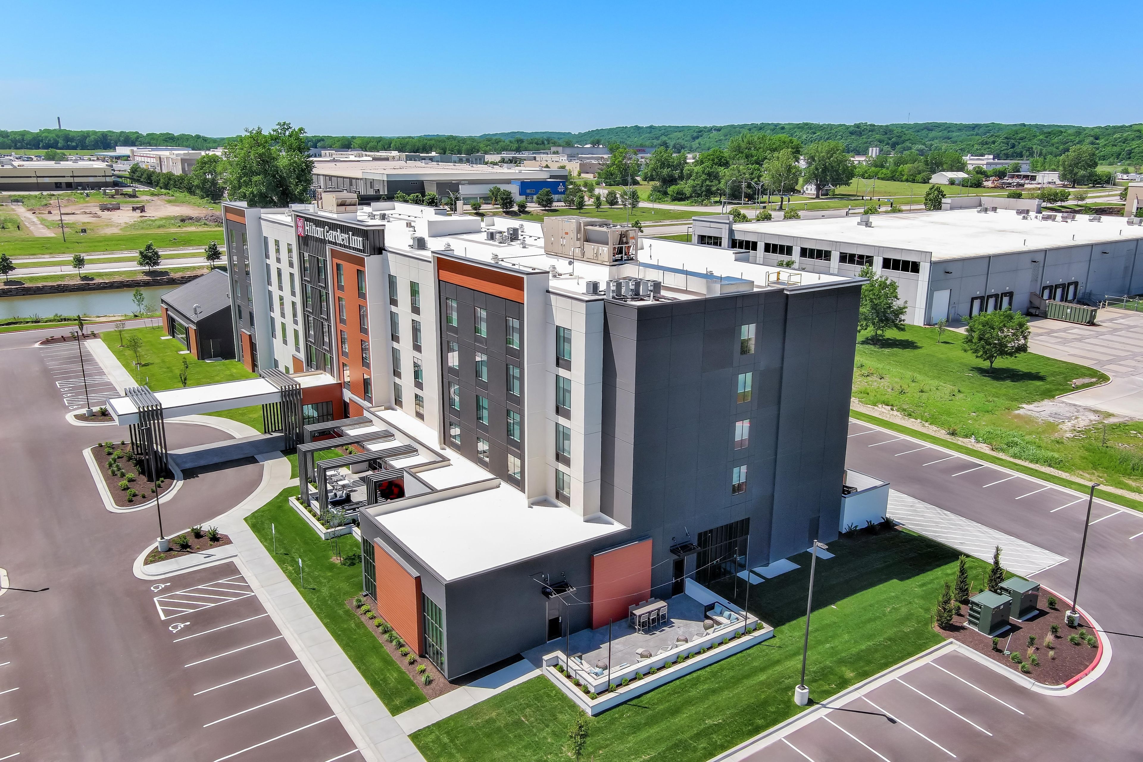 A modern hotel with a rooftop terrace, parking lot, and a view of the surrounding area.