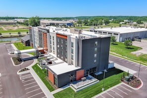 A modern hotel with a rooftop terrace, parking lot, and a view of the surrounding area.