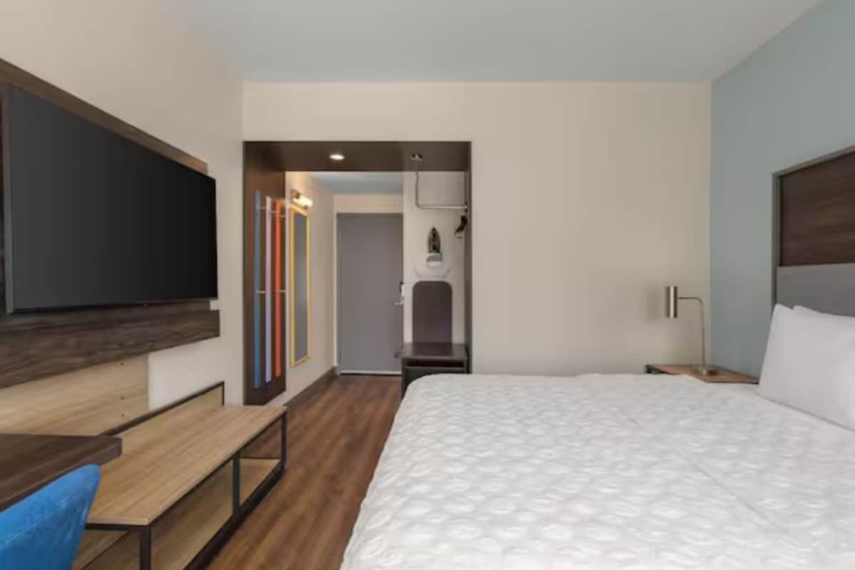 A hotel room with a bed, a desk, a chair, and a TV.