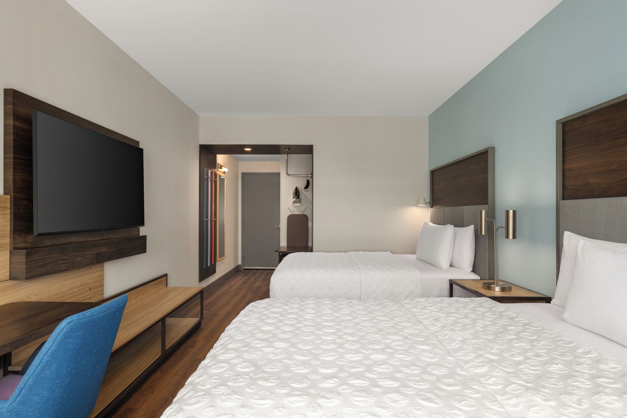 Habitación de hotel con una cama grande, un escritorio con silla, televisor y baño visible a través de una puerta abierta.