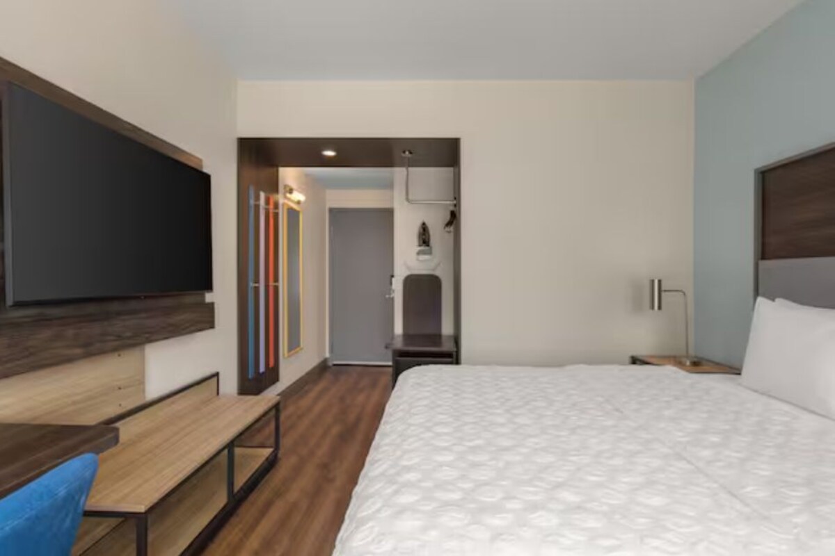 A hotel room with a bed, a desk, a chair, and a TV.