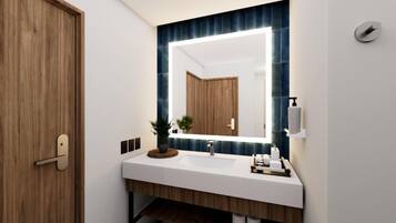 A modern bathroom with a wooden door, a white sink, a mirror with a blue-tiled backsplash, and a small plant on the counter.
