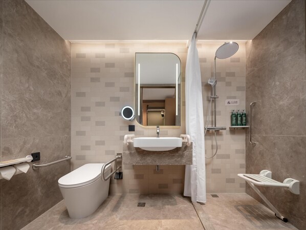 Ein modernes Badezimmer mit Toilette, Waschbecken, Spiegel, Dusche und Haltegriffen.