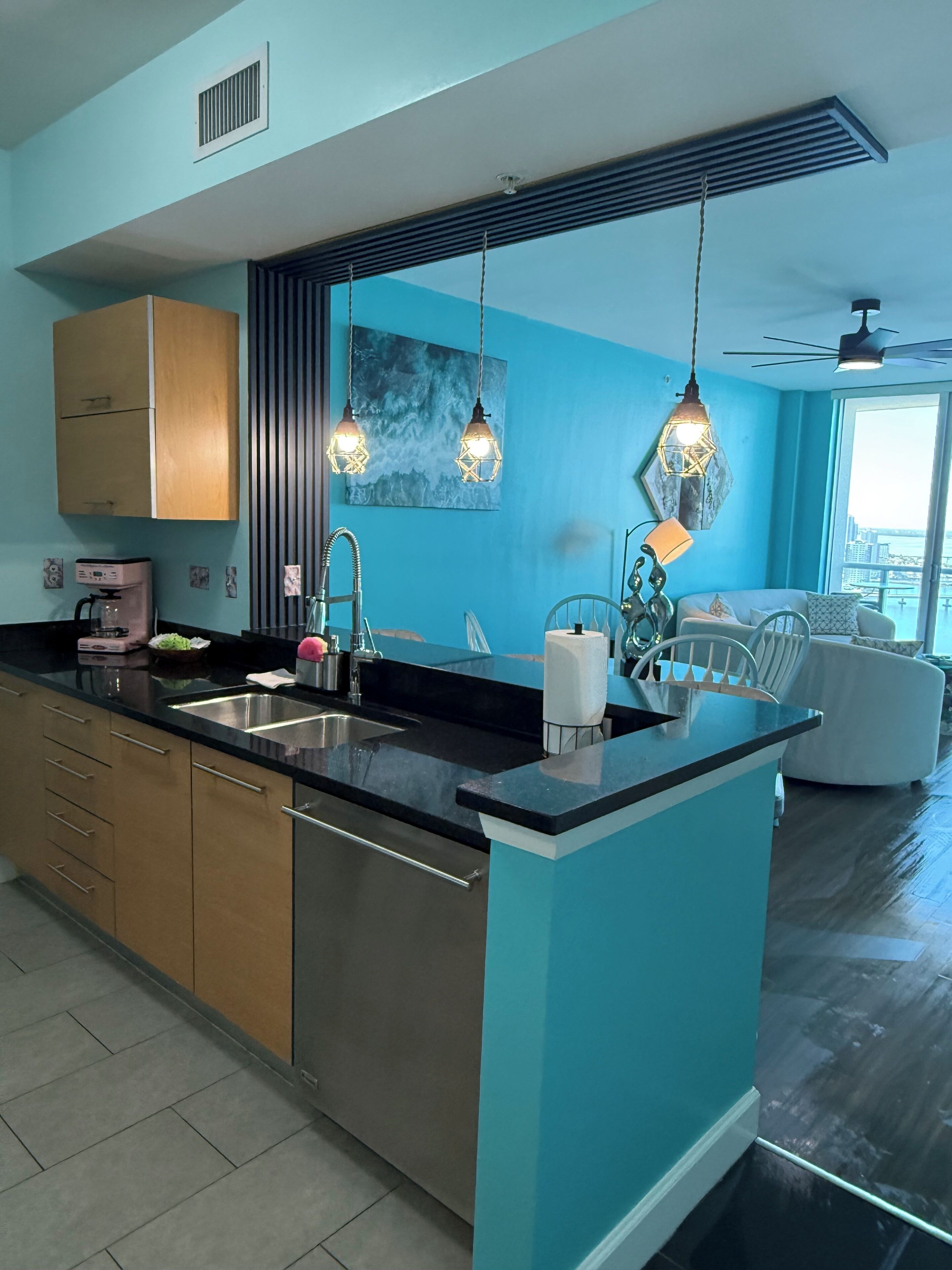 Una cocina moderna con una isla central, electrodomésticos de acero inoxidable e iluminación colgante.
