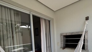Ein Zimmer mit Glastür zu einem Außenbereich, einer Hängematte und einem kleinen Fenster mit Dekoration.