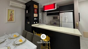 Eine moderne Küche mit Schwarz-Weiß-Design, einem eingebauten Ofen und einem Kühlschrank. Es gibt einen Essbereich mit einem Tisch für vier Personen und einem gelben Hocker.