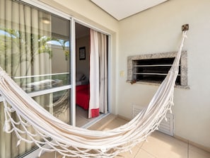 Een kamer met een hangmat, een schuifdeur met glas, een kitchenette en een wandplank.