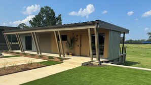 A modern building with a covered patio area, a well-maintained lawn, and a number '2' on the door.