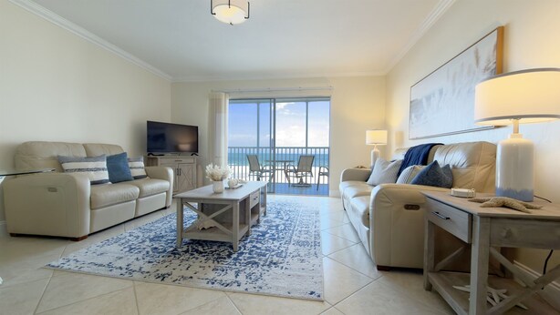 A living room with a sofa, TV, and a balcony with a view. - Gateway Villas #295 “Coastal Villa Reatreat” (Fort Myers Beach)