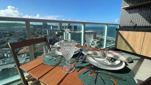 Ein Esstisch mit einer Glasvase, Tellern und Besteck auf einem Balkon mit Blick auf die Stadt.