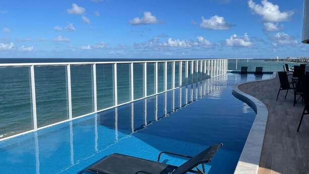 Ein Poolbereich mit Liegestühlen und Blick auf den Ozean.