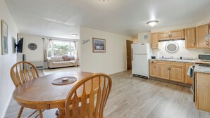 Una cocina amplia con armarios de madera, un refrigerador y un comedor con mesa y sillas de madera.