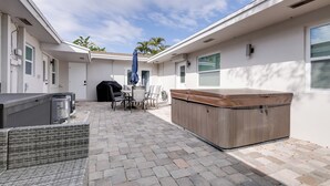 Eine Terrasse mit Whirlpool, Gartenmöbeln und einer überdachten Sitzgelegenheit.