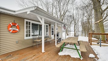 A covered porch with a wooden deck, a bench, and a picnic table.