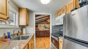 Una cocina con armarios de madera, un refrigerador de acero inoxidable, un microondas y un fregadero con encimera de granito.