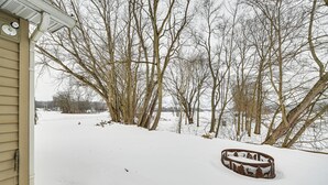 Un patio cubierto de nieve con un banco de madera y árboles.