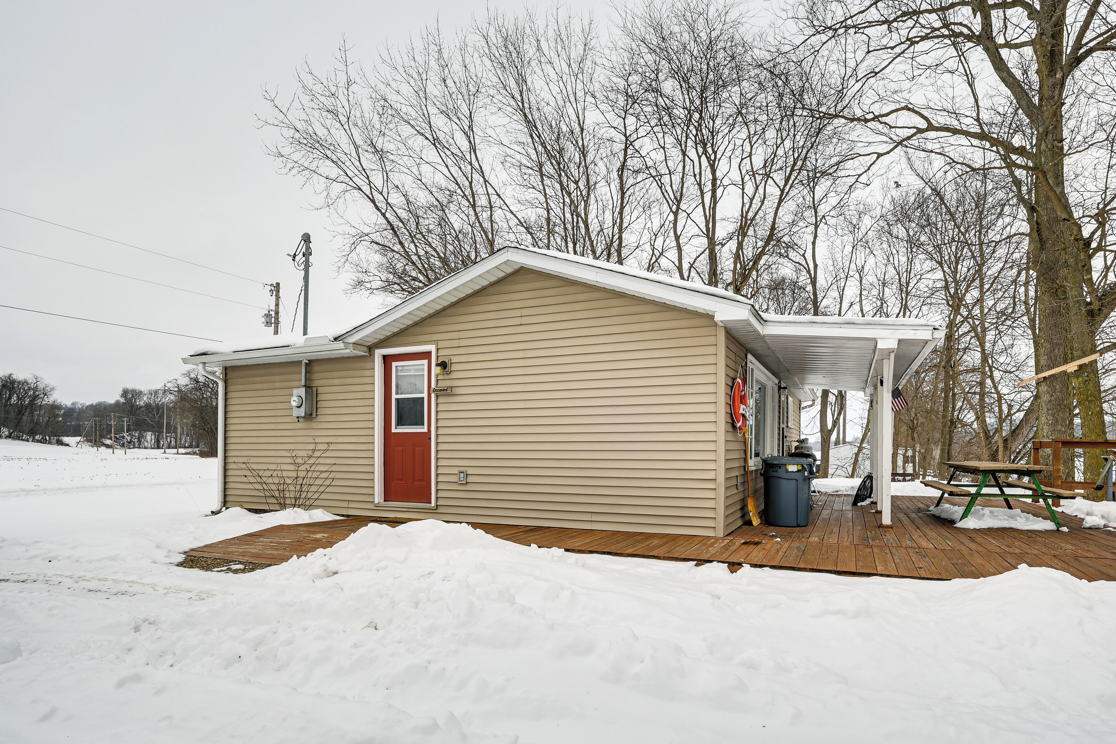 A small, single-story house with a red door and a covered porch area.