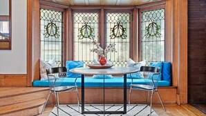 Un ventanal con una mesa de comedor y sillas, un sofá azul y coronas decorativas en las ventanas.