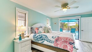 A bedroom with a bed, a nightstand, a ceiling fan, and a window with blinds. - Family Fun in Cape Coral! Colorful Home w/ Dock (Cape Coral)
