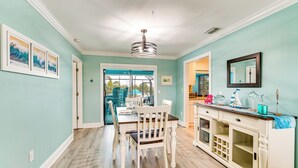 A dining area with a table and chairs, a kitchen area with cabinets and a countertop, and a view through a glass door to the outside. - Family Fun in Cape Coral! Colorful Home w/ Dock (Cape Coral)