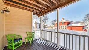 Une terrasse en bois avec deux chaises vertes et une balustrade blanche.