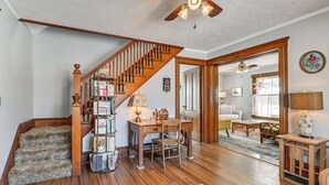 Un salon spacieux doté de planchers en bois franc, d’un escalier en bois, d’un bureau avec une chaise et d’une bibliothèque.