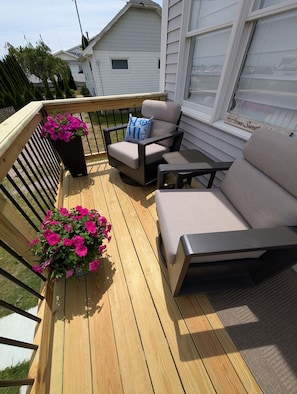 A deck with a sofa, a chair, and potted plants.