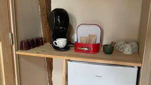Une petite cuisine équipée d’une machine à café, d’un petit réfrigérateur et d’une poubelle.