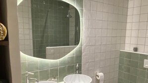 Une salle de bain moderne avec deux lavabos blancs, un grand miroir et des toilettes.